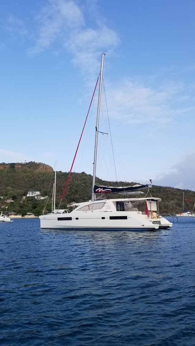 Our catamaran at anchor off a green hillside